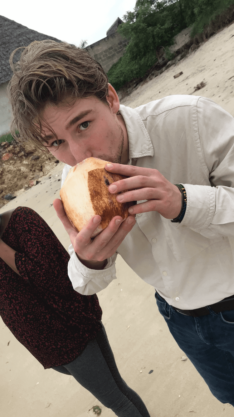 A picture of me at the beach drinking from a coconut